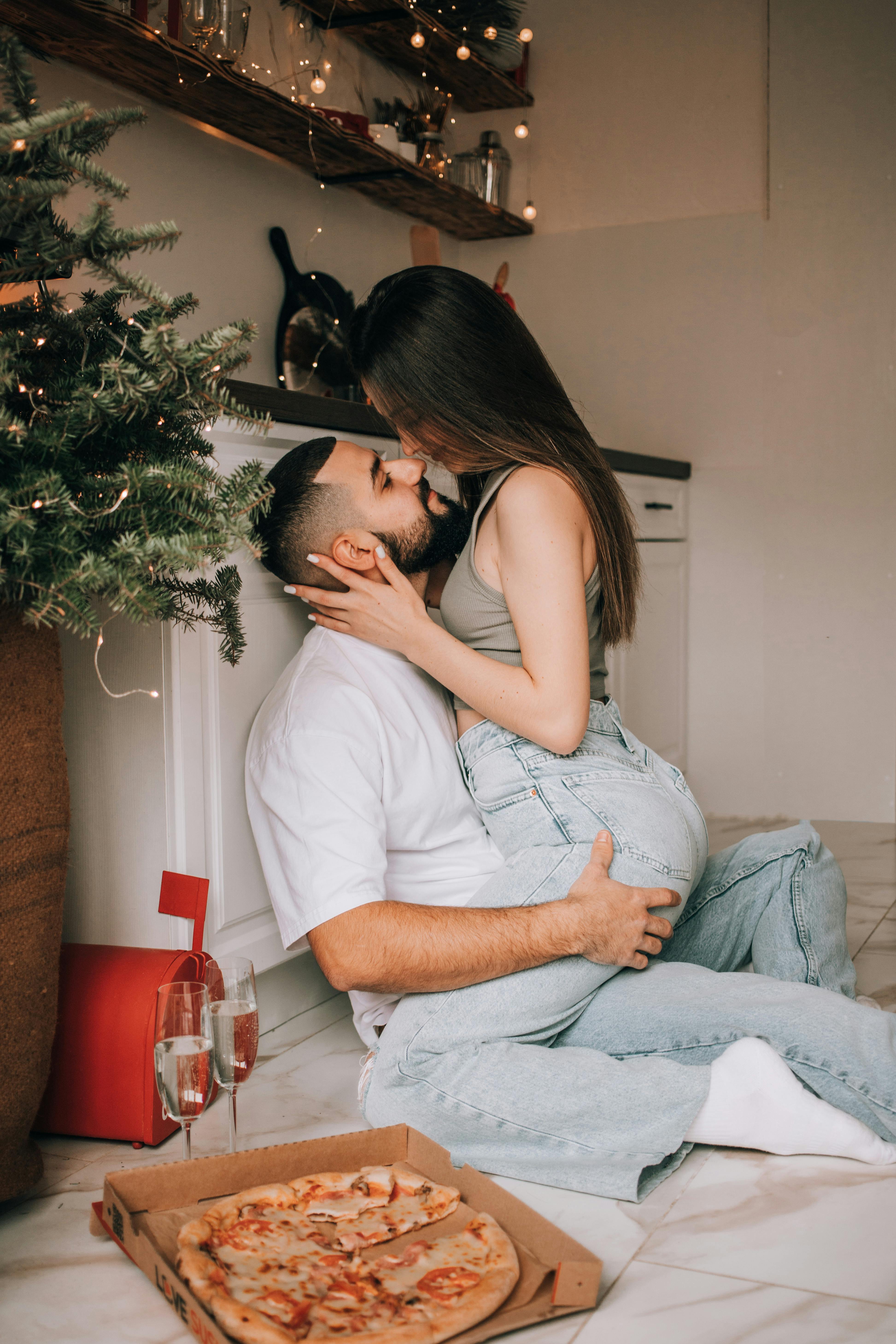 Couple sharing a romantic moment by the Christmas tree in a cozy kitchen setting.