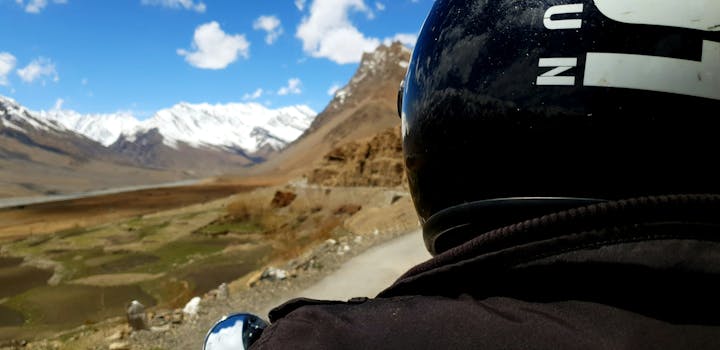A motorcyclist enjoys a scenic ride along a mountainous road under clear blue skies.