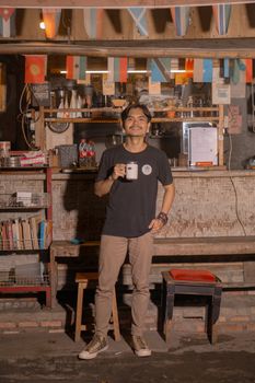 Casual setting with a man holding coffee in a rustic Indonesian cafe. Warm and inviting vibe. - Fotografer Sidoarjo