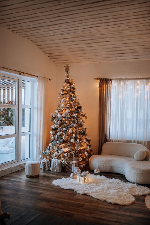 christmas-living-room-hero Cozy Christmas living room with a decorated gold-and-white tree, curved sofa and fairy lights