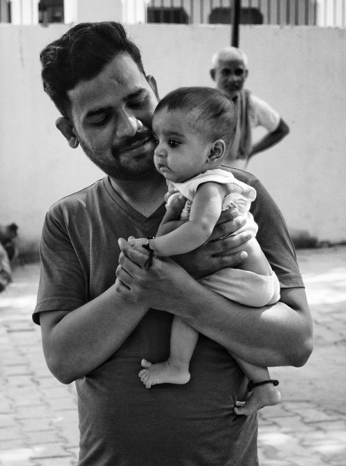 Free A candid black and white photo of a father cradling his baby in India. Stock Photo
