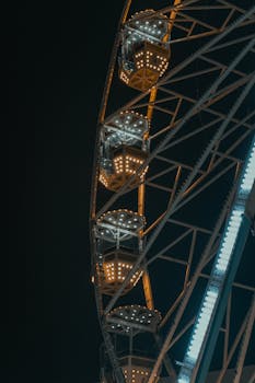Illuminated Ferris wheel in Korçë, Albania, captured at night showcasing vibrant lights and structure.