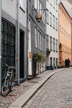 Quaint street in Copenhagen featuring bicycles, cobblestone path, and colorful historic buildings.