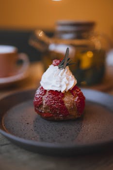 Delicious raspberry pastry with whipped cream on a dark plate indoors.