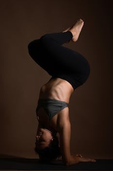 Elegant headstand yoga pose captured with minimalist lighting, showcasing strength and balance.