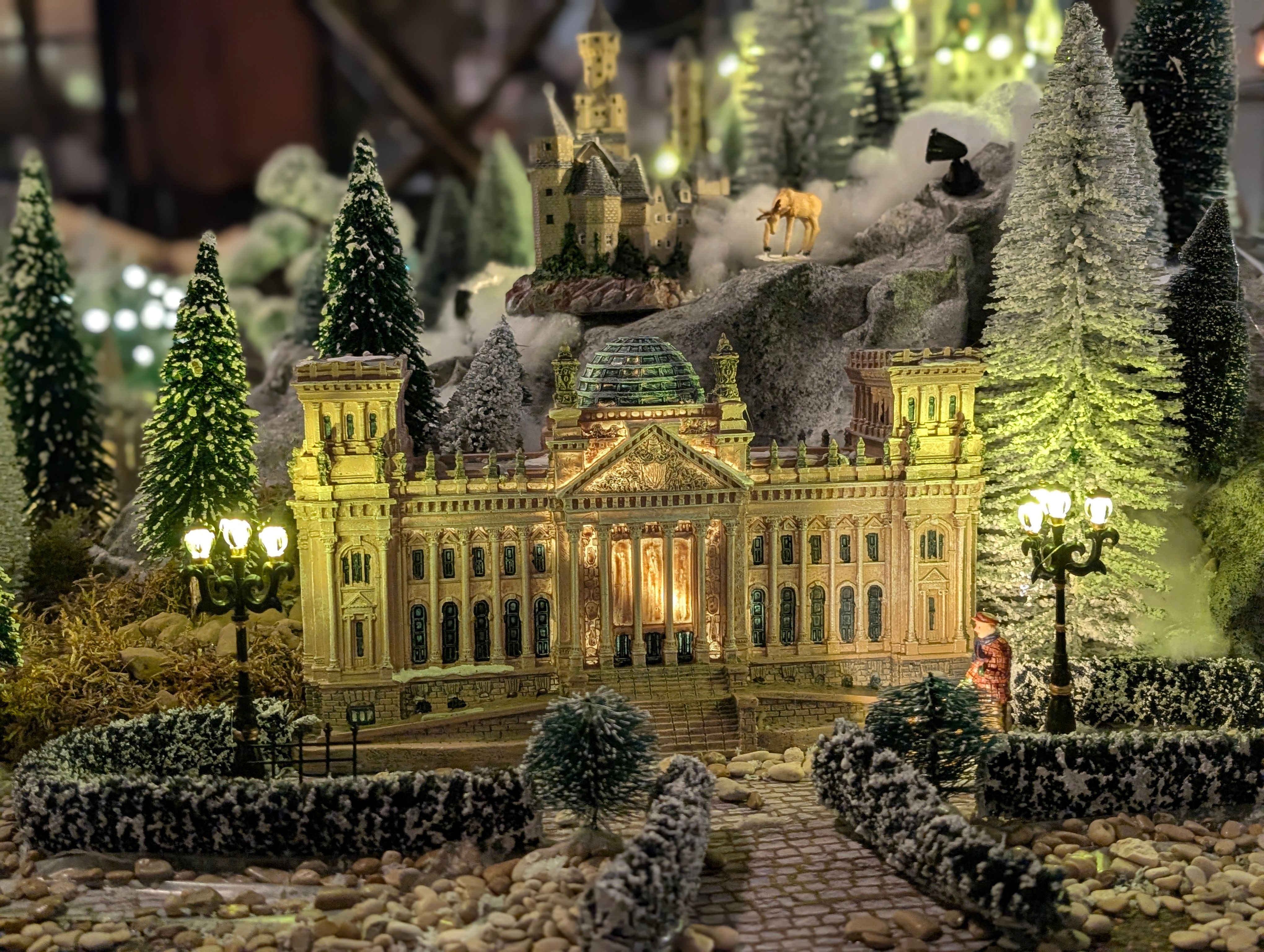 Detailed miniature landscape with illuminated castle, trees, and snow. Perfect for holiday displays.