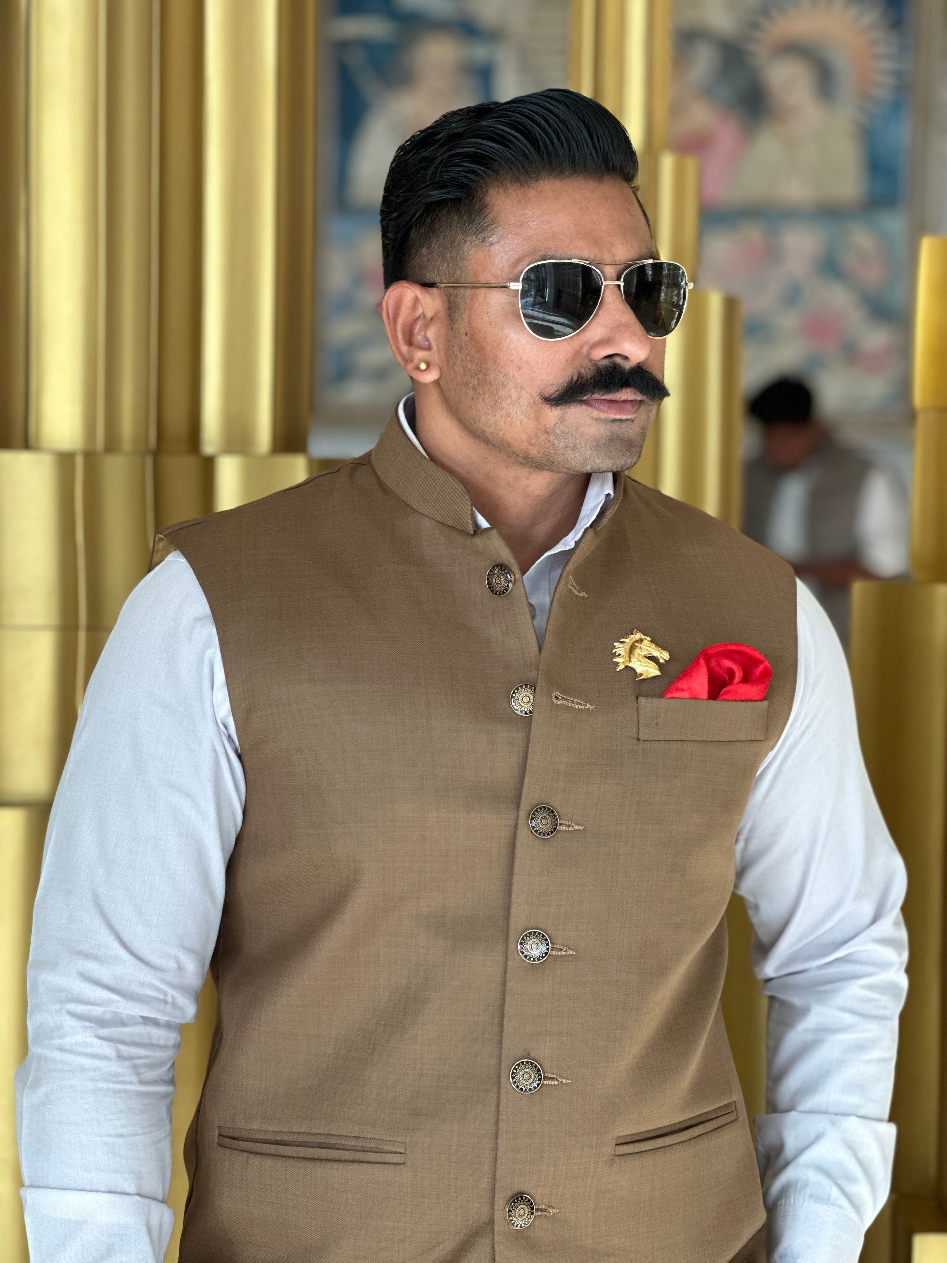 Fashionable man in sunglasses and brown vest posing confidently indoors.