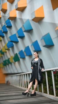 Stylish woman poses elegantly against a vibrant geometric wall, exuding modern fashion.