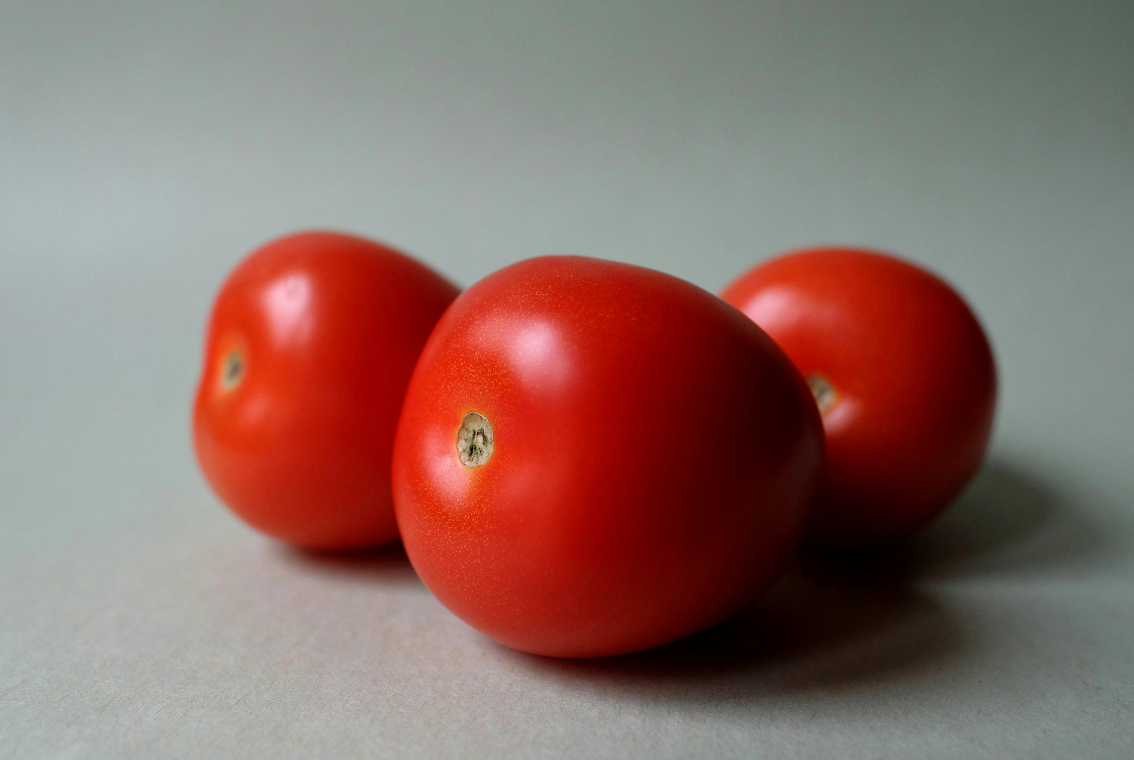 Three ripe red tomatoes arranged on a neutral background. Fresh and vibrant.