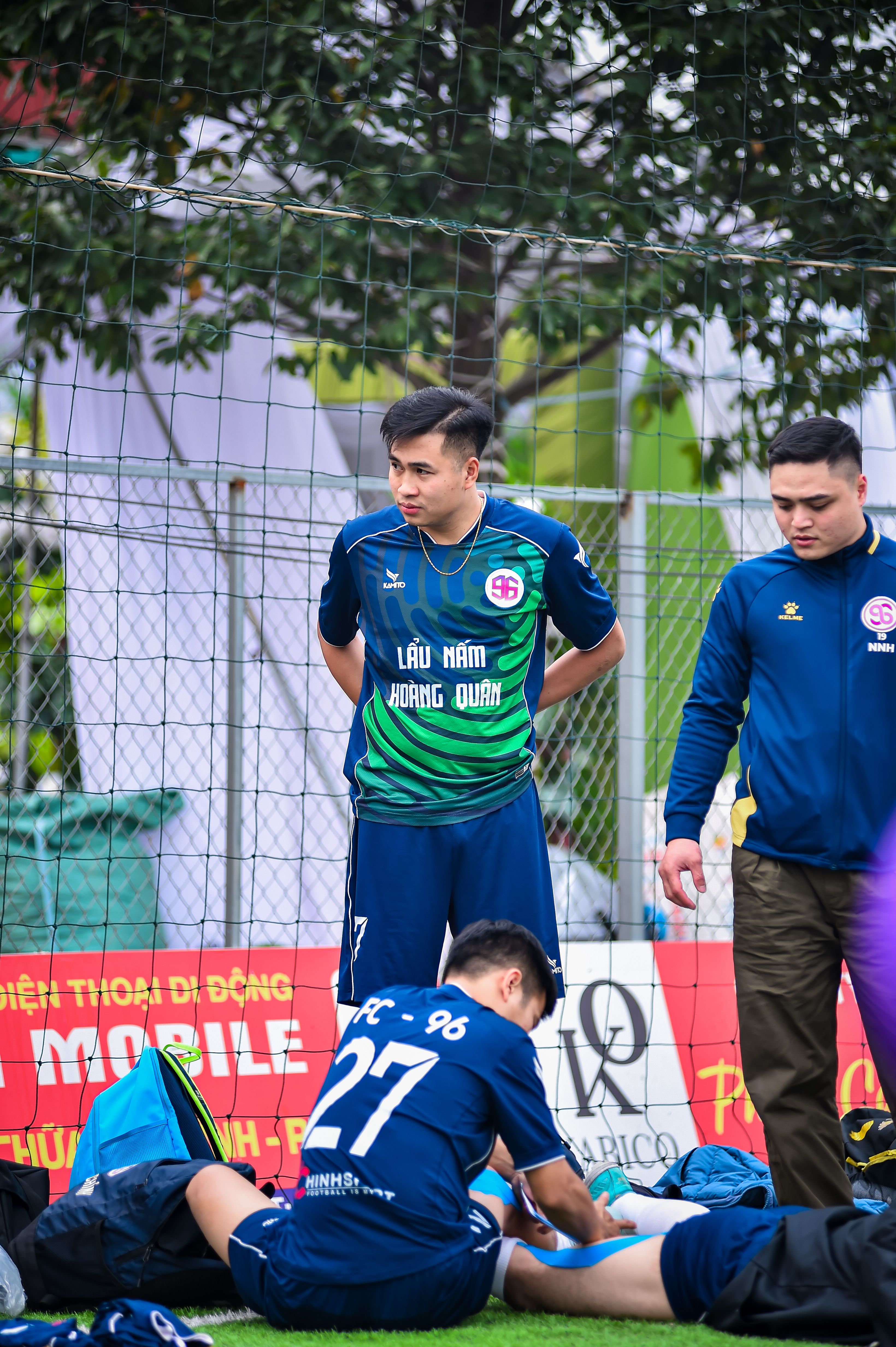 Football players taking a break on an artificial turf field in Hà Nội, Việt Nam.