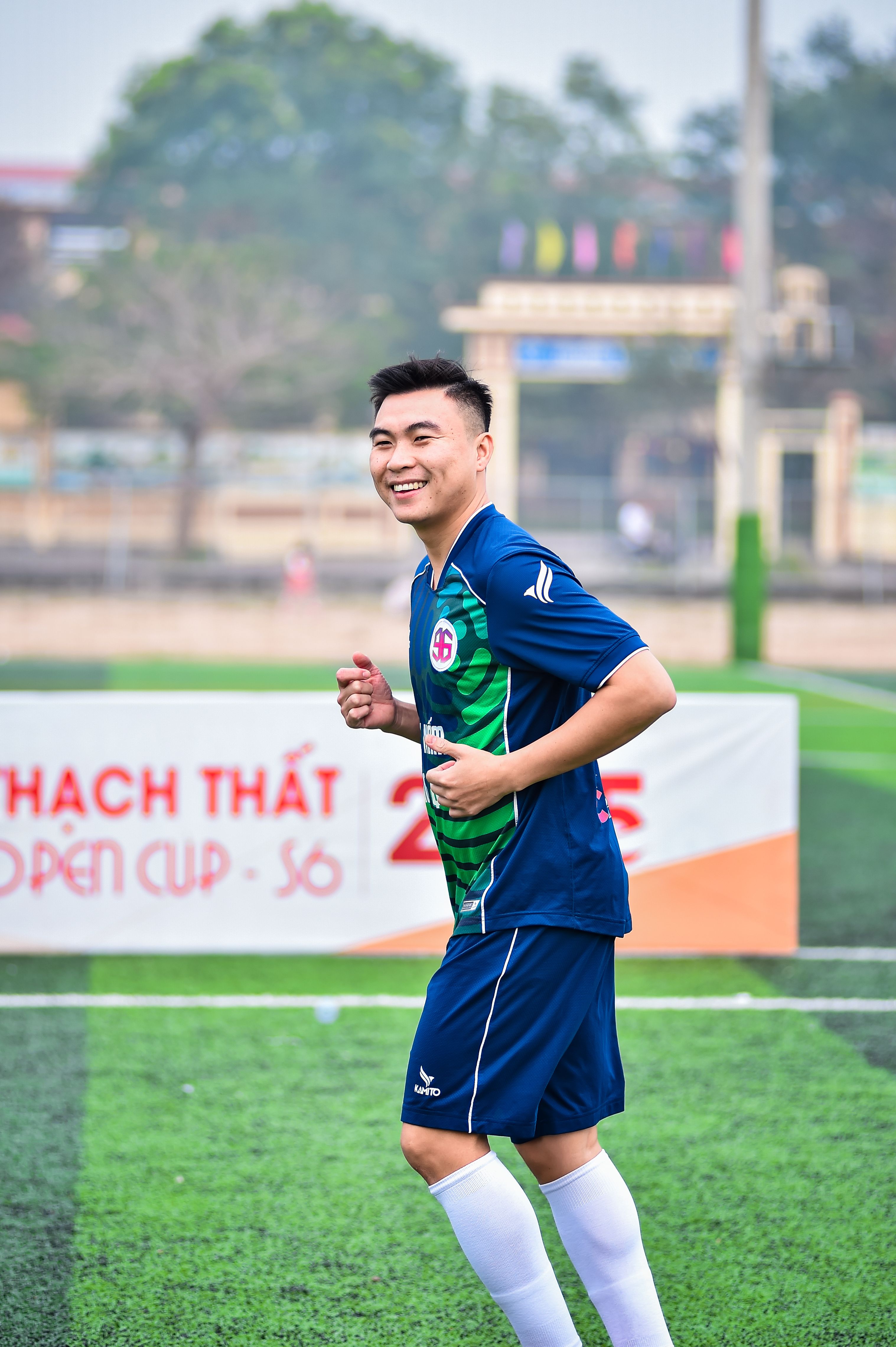 Smiling football player on an artificial turf field during a match in Hà Nội, Vietnam.