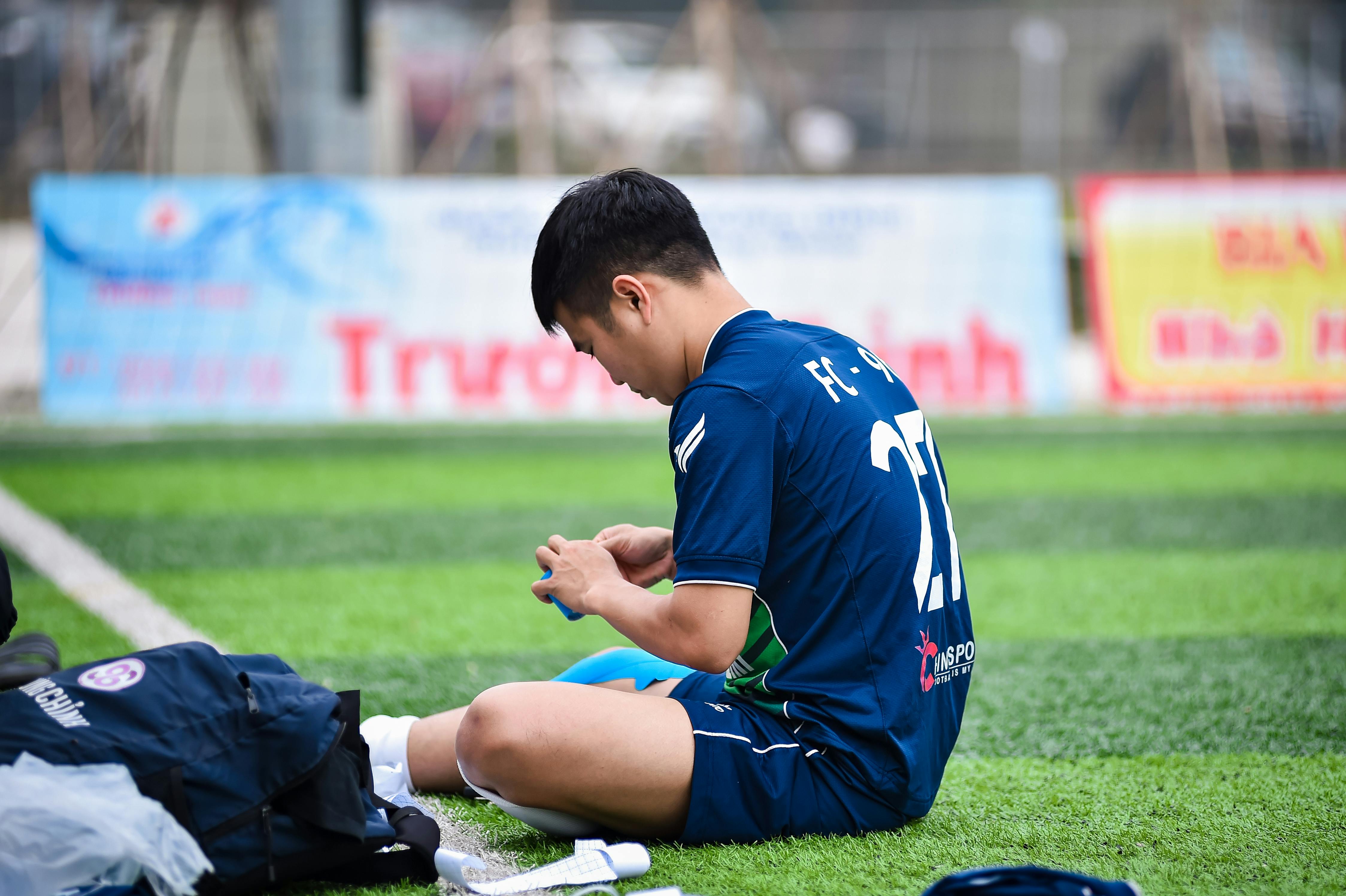 A young football player seated on artificial turf prepares for a game in Hanoi, Vietnam.