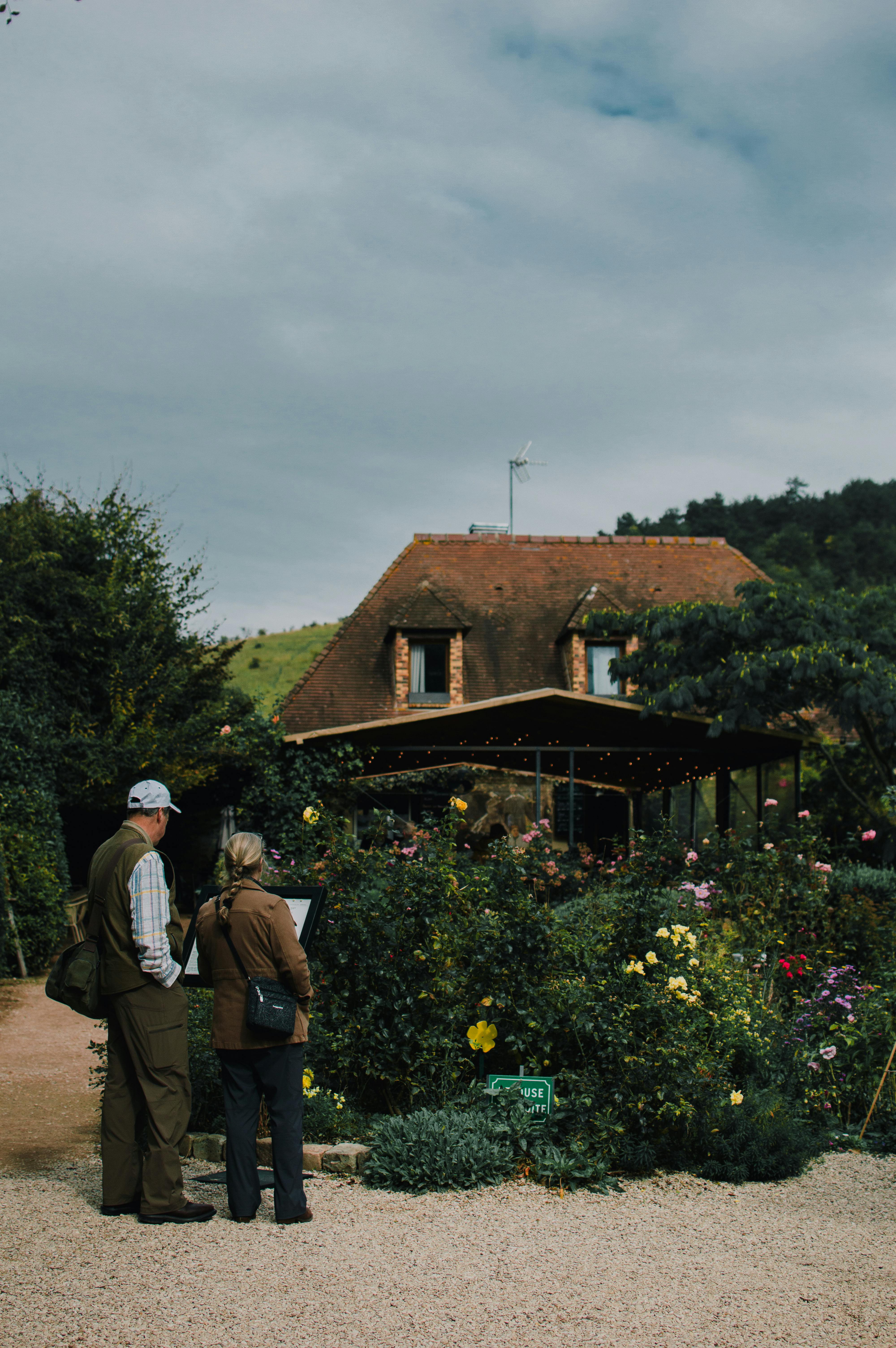 Visitors admire a garden in Giverny, France with a charming cottage backdrop.