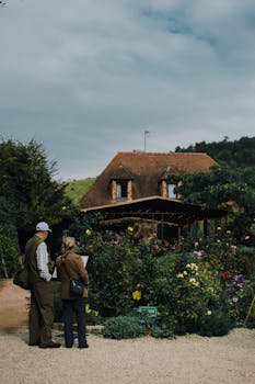 Visitors admire a garden in Giverny, France with a charming cottage backdrop.