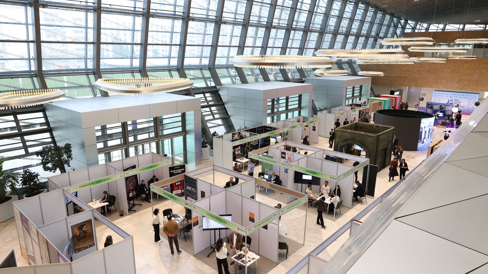 A bustling trade show exhibition inside a modern hall with people networking and exploring booths.