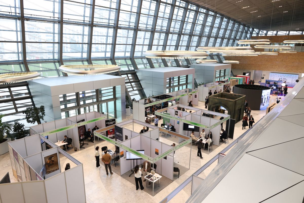 A bustling trade show exhibition inside a modern hall with people networking and exploring booths.