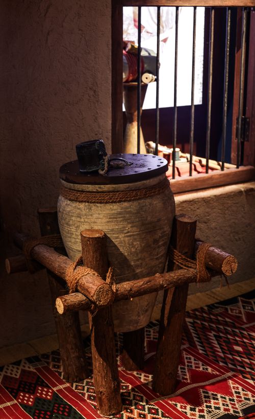 Free Rustic clay pot on wooden stand, lit by sunlight through a window, indoors. Stock Photo