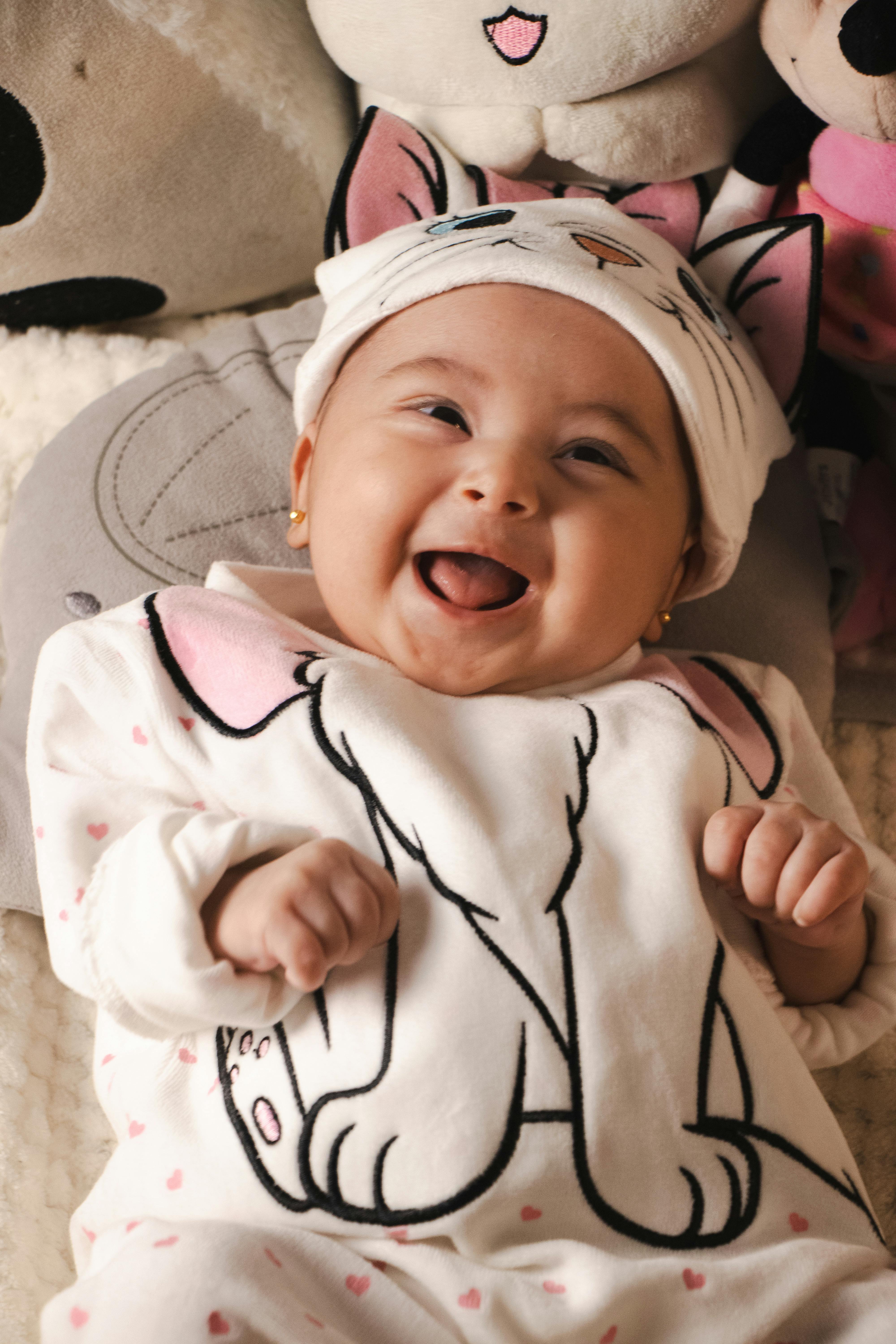 Cute baby wearing a cat-themed outfit and smiling joyfully indoors.