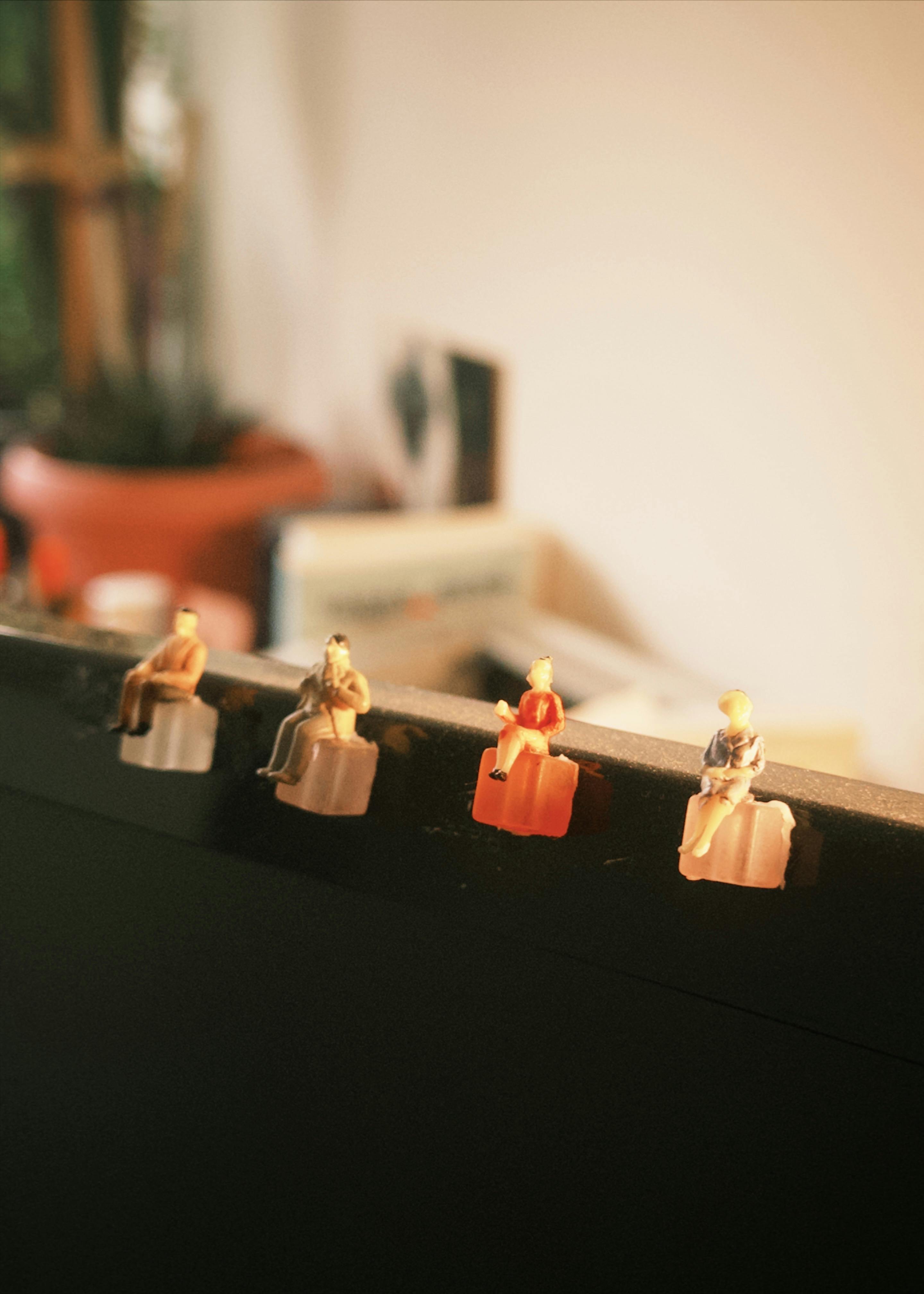 Kostnadsfria Miniatyrfigurer sitter på en skärm i en kontorsmiljö och skapar en unik konstnärlig uppvisning. Stock foto