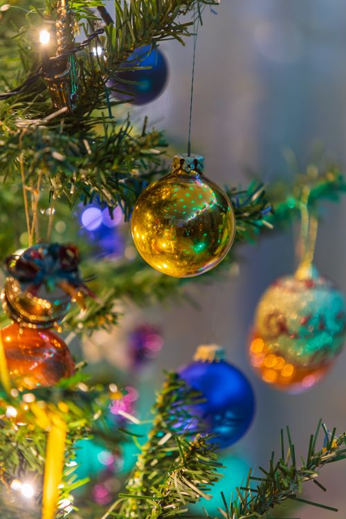Free Close-up of colorful Christmas ornaments on a decorated tree branch with blurred lights. Stock Photo