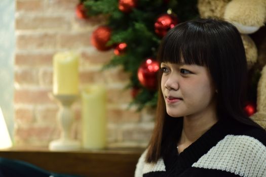 Portrait of a young woman indoors near a decorated Christmas tree.