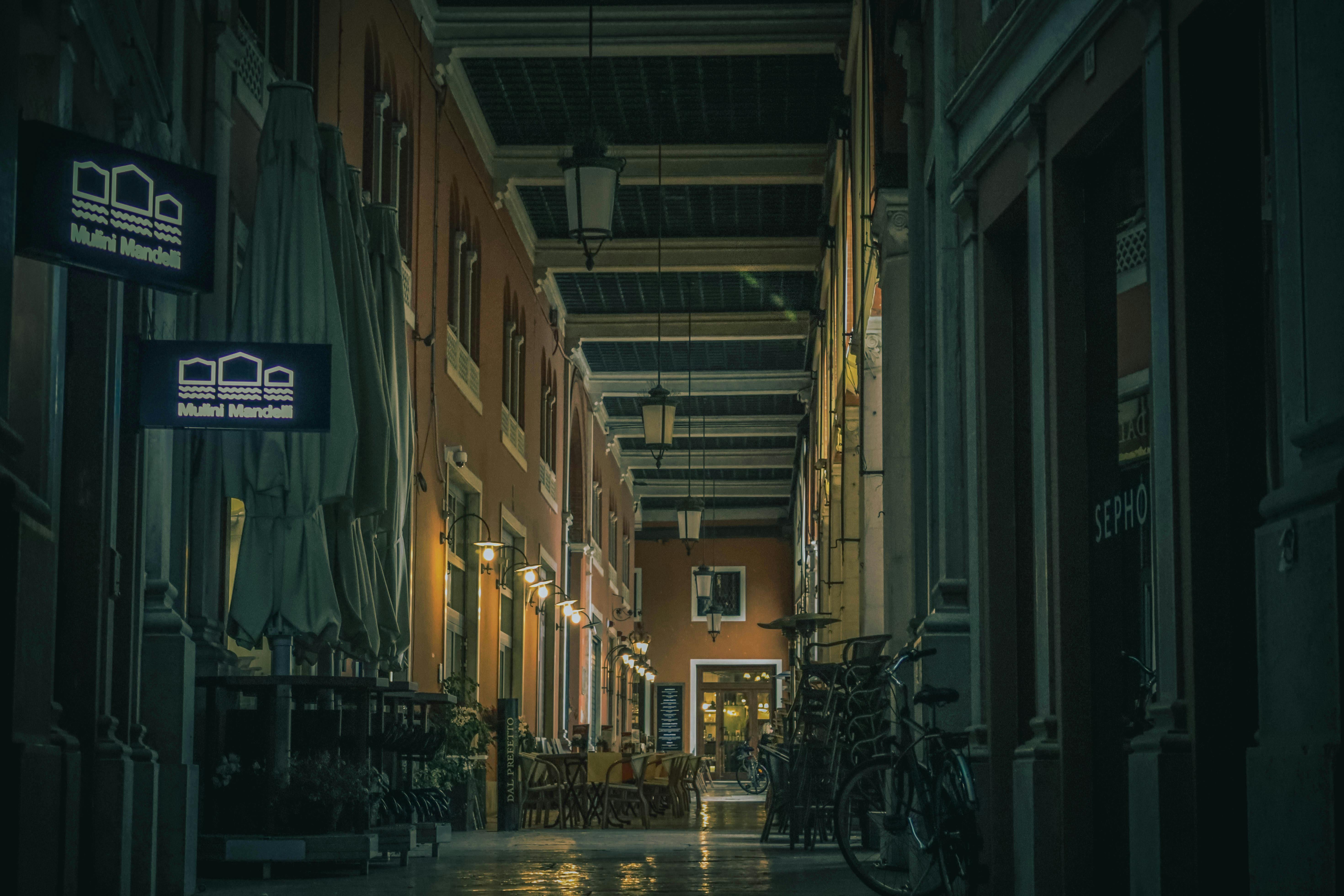 Free Cozy European corridor with shops and bicycles under evening lights, ideal for travel themes. Stock Photo