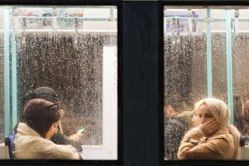 Free View of passengers on a rainy day through a wet public transit window. Stock Photo