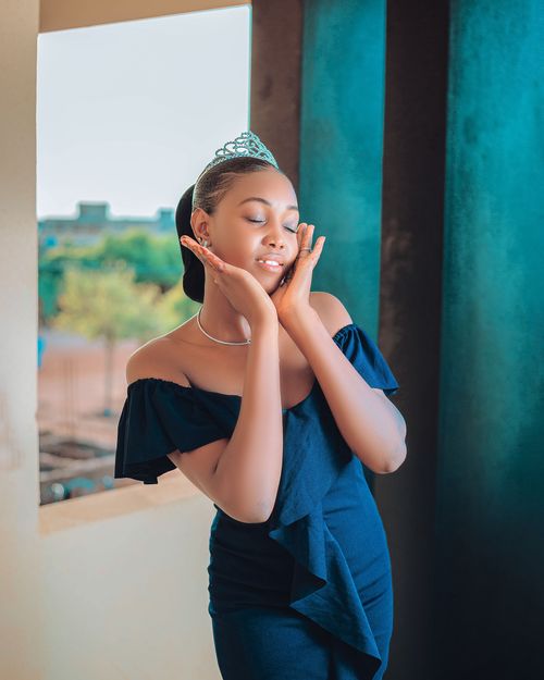 Free A woman in a black dress and tiara posing gracefully by the window. Stock Photo