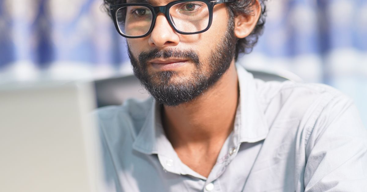 An Indian software developer focused on code at a laptop while building an AI feature.