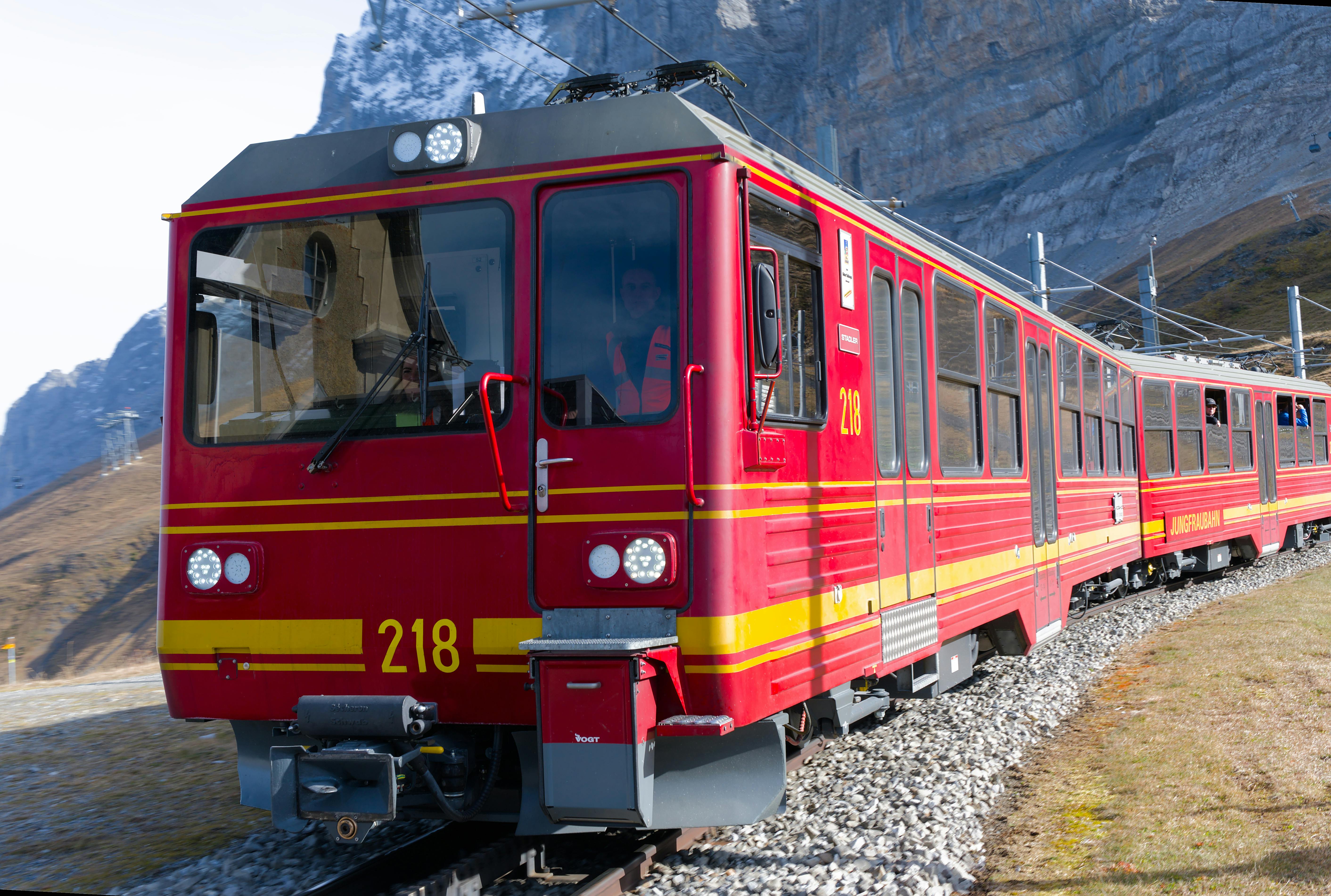 Red mountain train traversing the scenic Jungfraujoch landscape on a clear day.