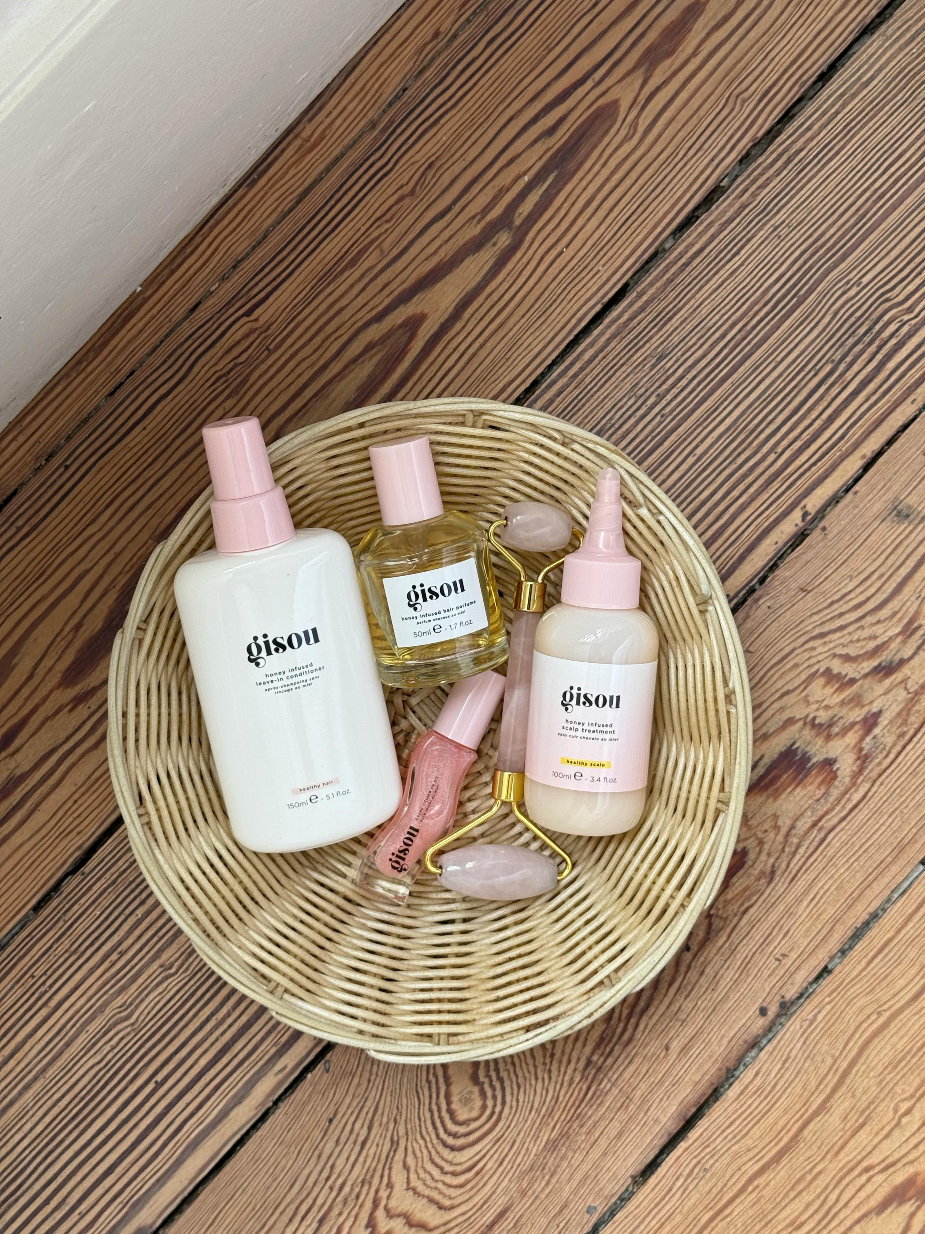 A collection of beauty products in a wicker basket placed on a wooden floor.