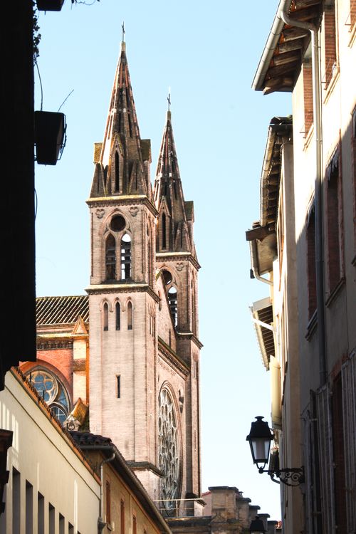 Free Sunlit view of historic church towers from a narrow urban street, showcasing Gothic architecture. Stock Photo