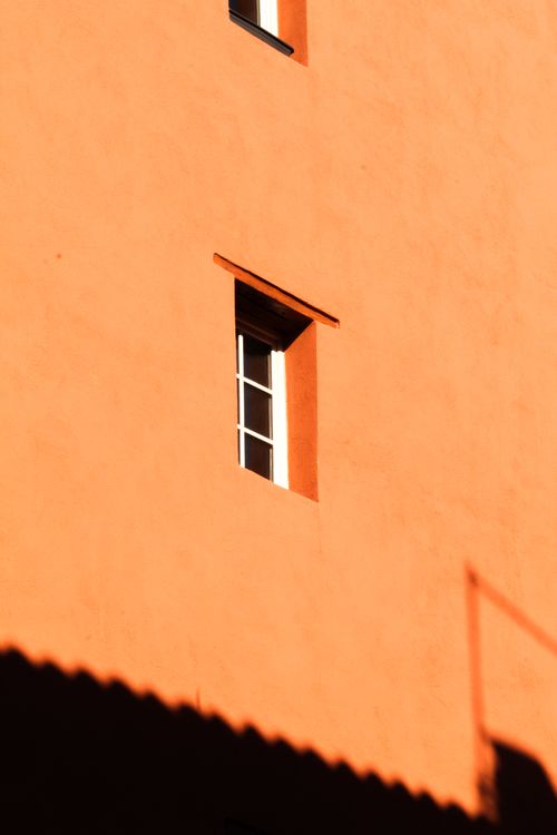 Free Abstract view of a single window on an orange wall, featuring strong shadows. Stock Photo