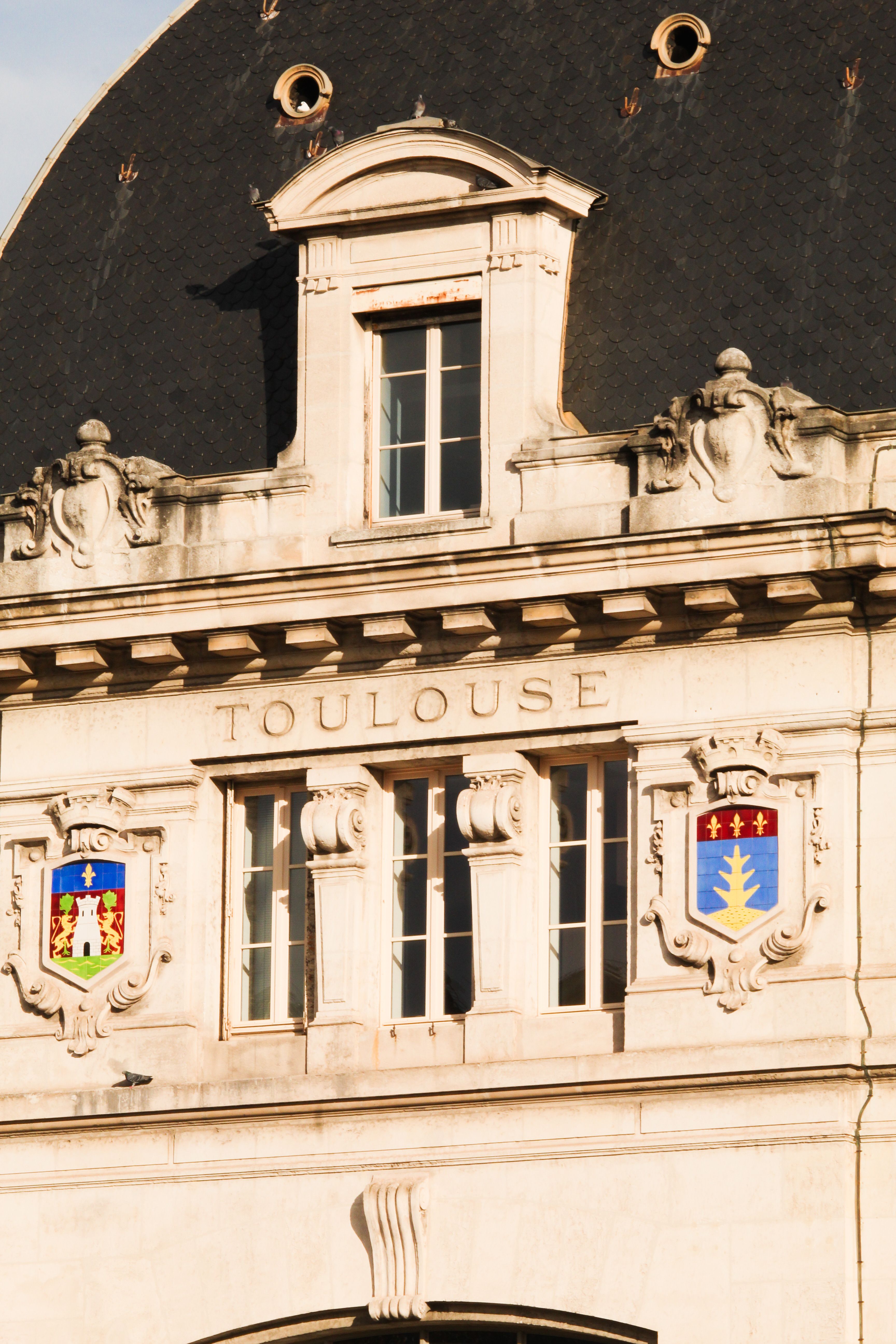 Close-up of an ornate historic building facade in Toulouse, featuring intricate stonework and architectural details.