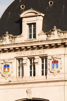 Close-up of an ornate historic building facade in Toulouse, featuring intricate stonework and architectural details.