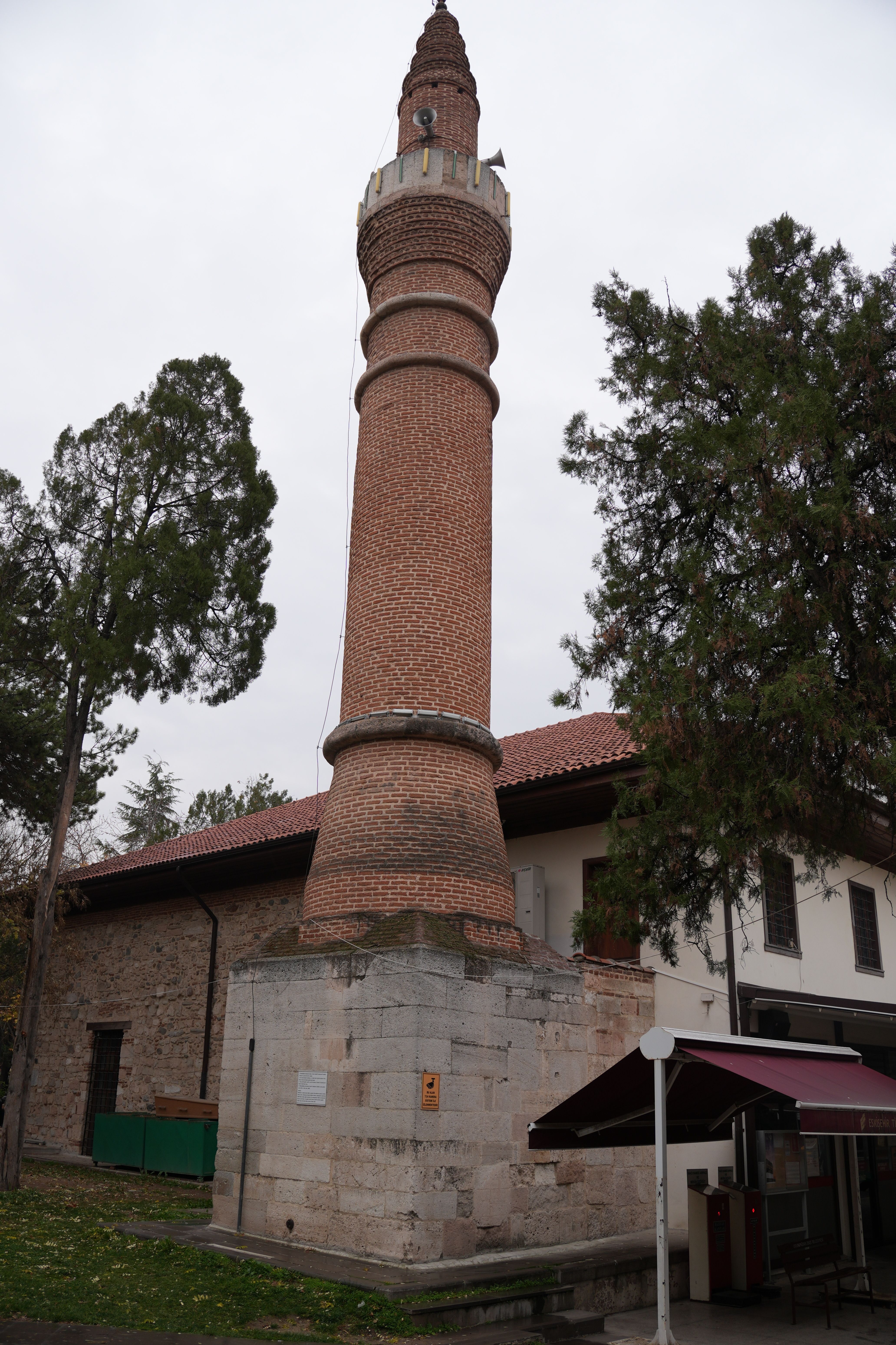A tall, historic brick minaret stands amidst trees in an outdoor setting, showcasing classic architecture.