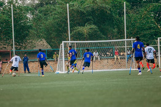 A vibrant scene of an outdoor soccer game played by athletes with prosthetics on a green field.