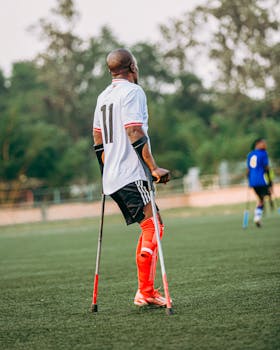 A soccer player with crutches participates actively on the field, showcasing determination and skill.
