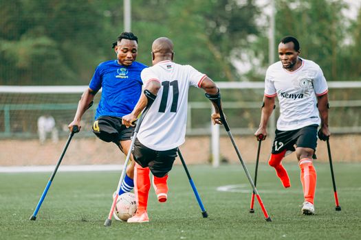 Athletes with disabilities play an intense game of adaptive football on a green field.