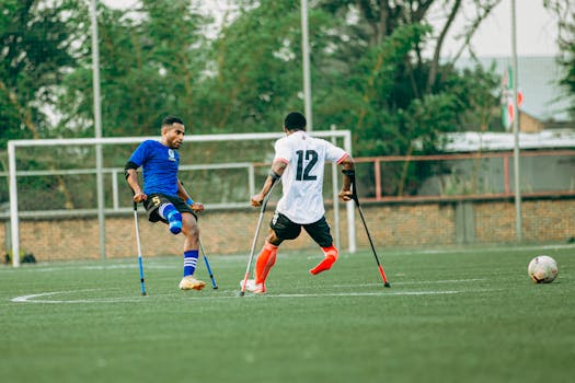 Two athletes with disabilities play soccer using crutches, showcasing inclusivity and sportsmanship.