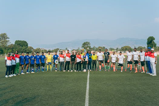 Amateur soccer players with crutches lined up on a field, ready for a match, on a sunny day.