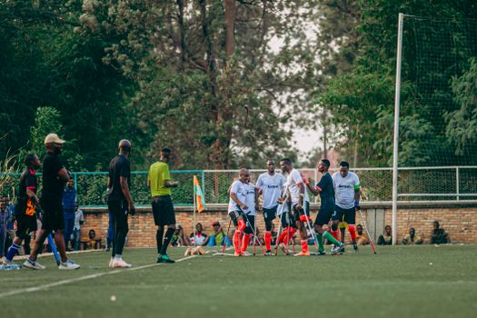 Group of amputee athletes playing soccer on a field during daytime.
