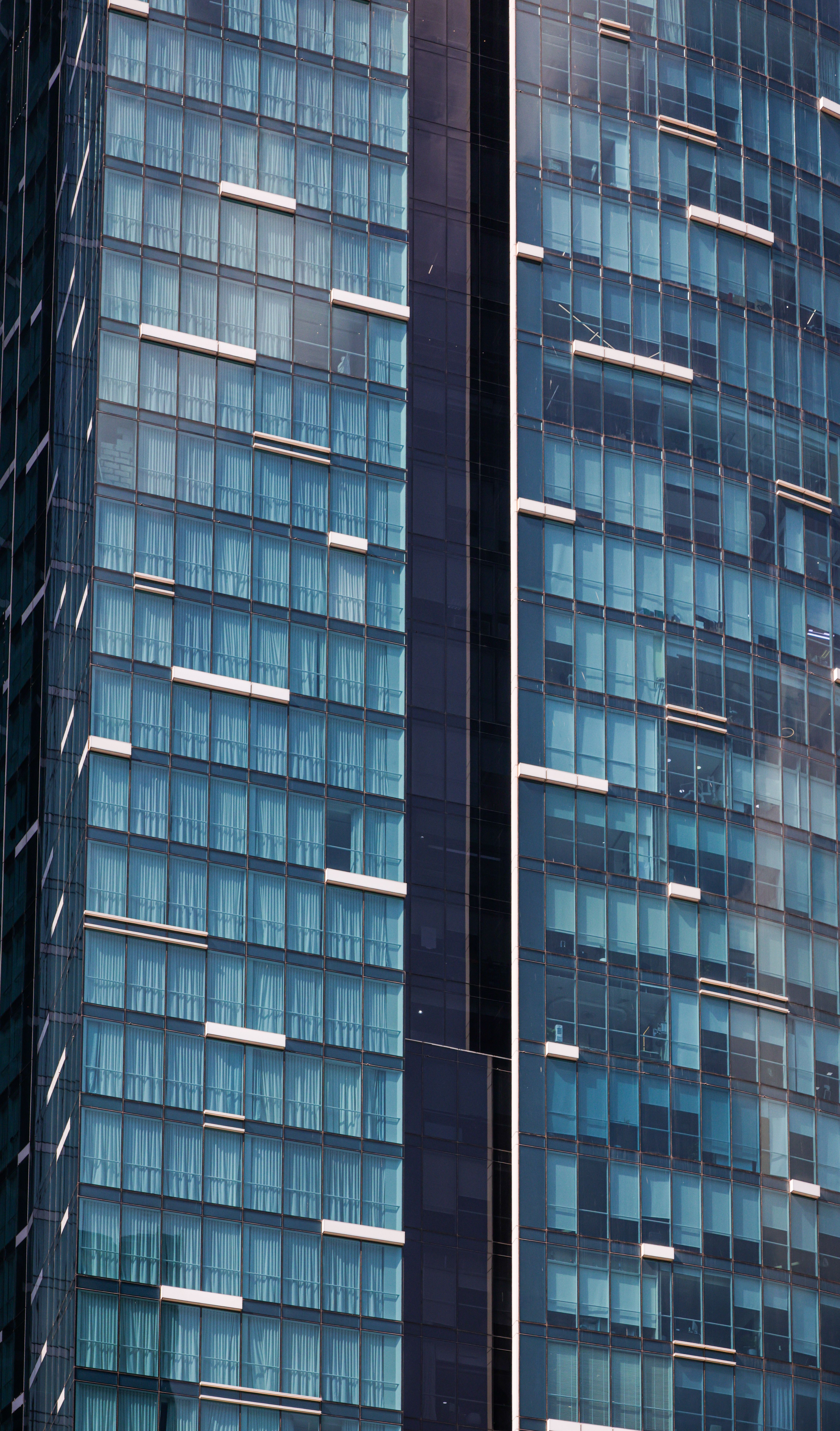 Fotomural Vista en primer plano de un rascacielos moderno con fachada de vidrio que refleja la arquitectura urbana.