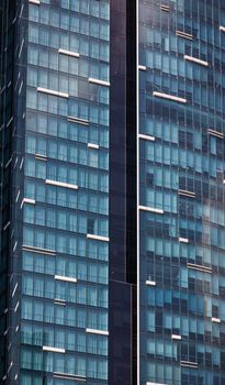 Close-up view of a modern skyscraper with a glass facade reflecting urban architecture.