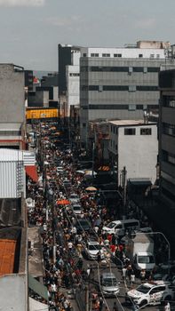 A bustling city street filled with people and vehicles on a sunny day.