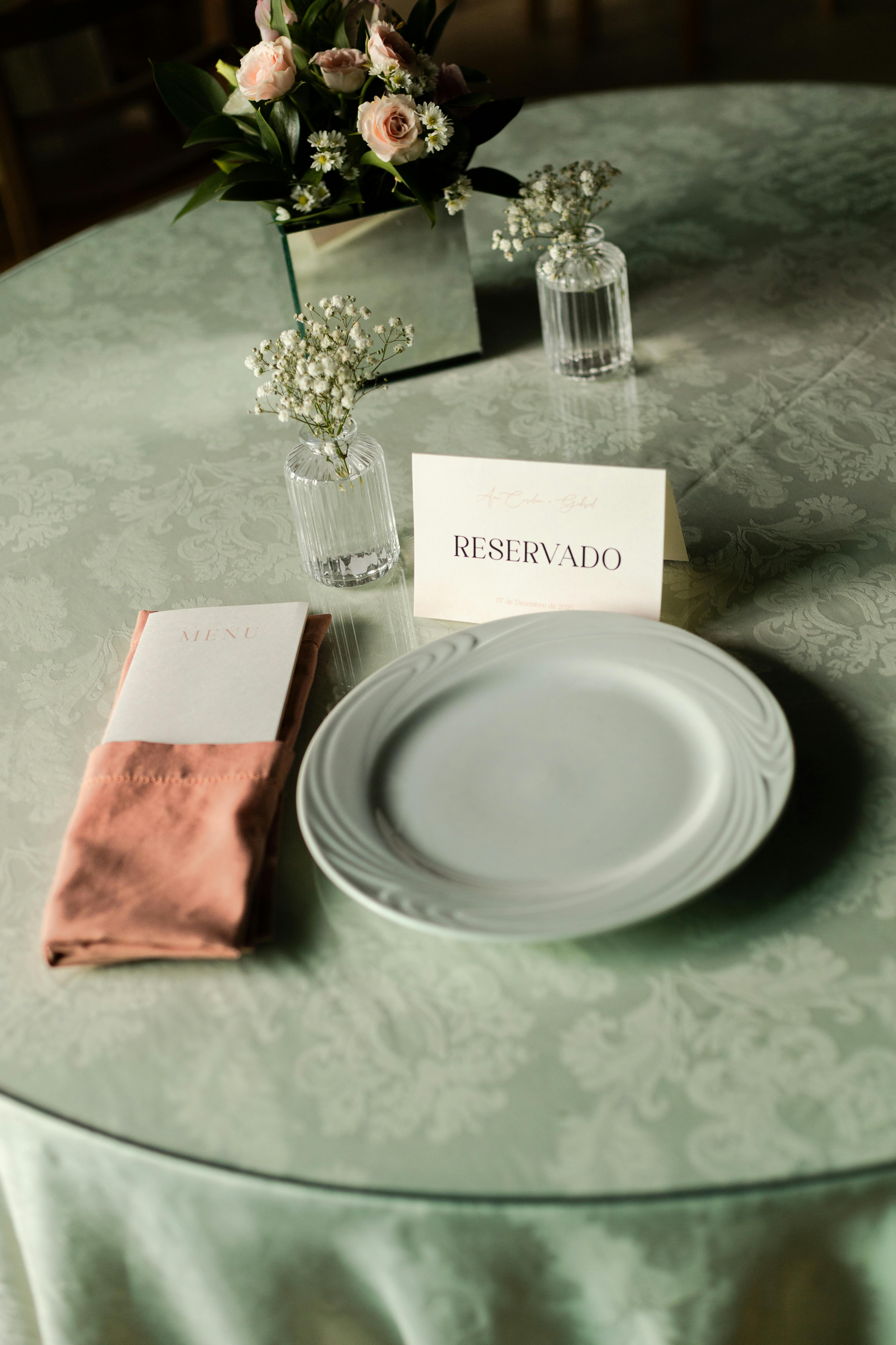 Beautifully set wedding table with 'Reservado' card, floral centerpiece, and elegant dinnerware.