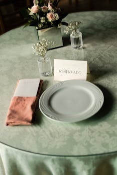 Beautifully set wedding table with 'Reservado' card, floral centerpiece, and elegant dinnerware.