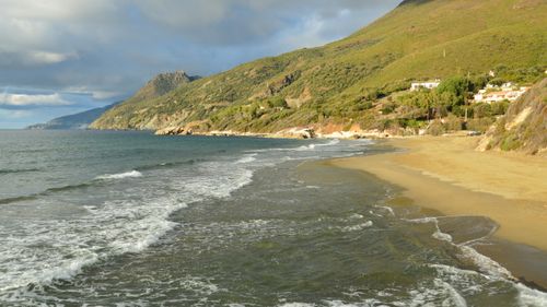 Free Idyllic view of Farinole beach in Corsica, France, with lush mountains and clear sea waves. Stock Photo