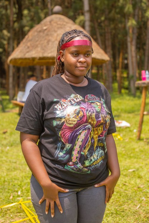 Free Young woman in graphic tee at an outdoor event with traditional hut background. Stock Photo