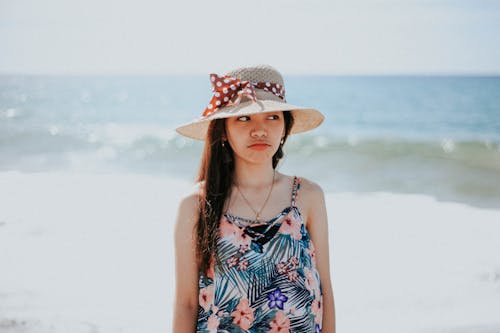 Woman in Blue and White Floral Tank Top Wearing Sun Hat
